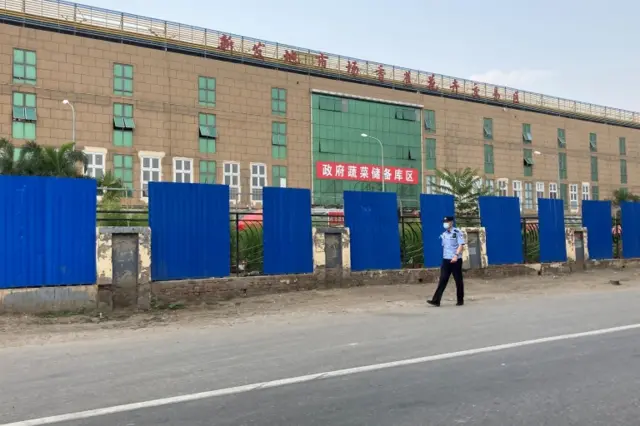 A police officer wearing a face mask walks outside the Xinfadi wholesale market in Beijing, China June 13, 2020.