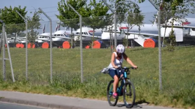 A woman bikes past the BA fleet