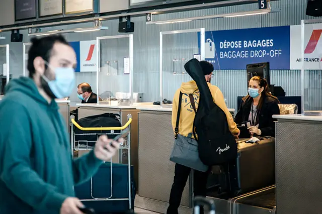 Travelers wearing protective face masks drop of their luggage