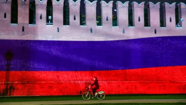 Woman on bike riding past Kremlin building in Moscow