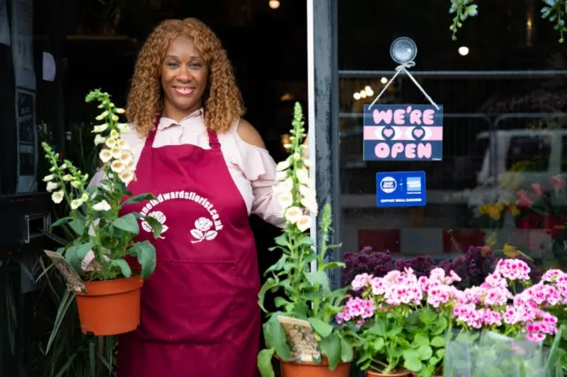 A shopkeeper in London displays a "we're open" sign