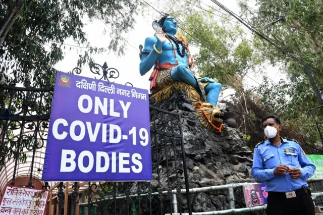 A Security guard stands guard near an Idol of Lord Shiva in the Punjabi Bagh cremation ground, designated for covid-19 victims funerals in Delhi