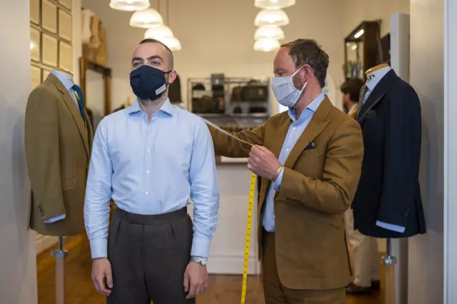 Customer and tailor with masks in Savile Row