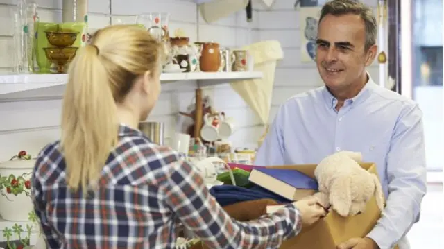 A woman donating to a charity shop