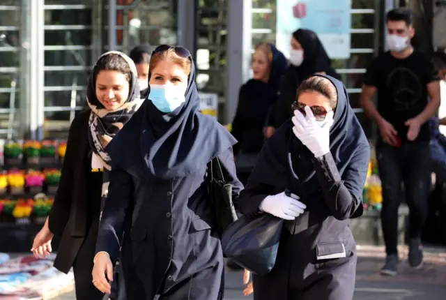 Iranian women wearing face masks and protective gloves walk in a street in Tehran, 14 June 2020