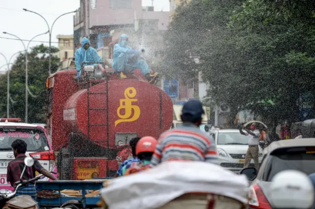 A firefighter (C) sprays disinfectant as a preventive measure against the spread of the COVID-19 coronavirus in a containment zone in Chennai on May 11, 2020.