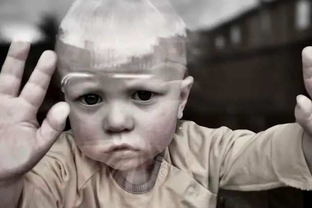 A portrait of a toddler looking out of a window