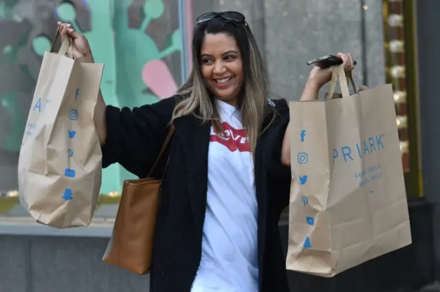 A woman holding up her Primark bags