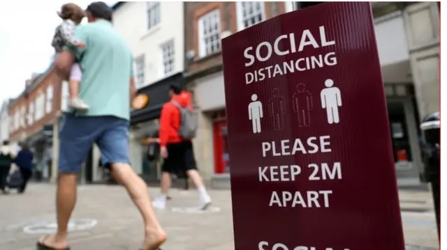 A man walking past a social distancing sign