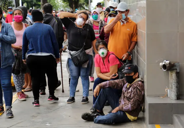 People queue outside a bank to collect government aid bonuses, in the Amazon city of Iquitos, in the Peruvian Loreto region, on June 15, 2020