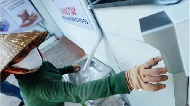 A woman pushing a button to dispense free rice from a "rice ATM"