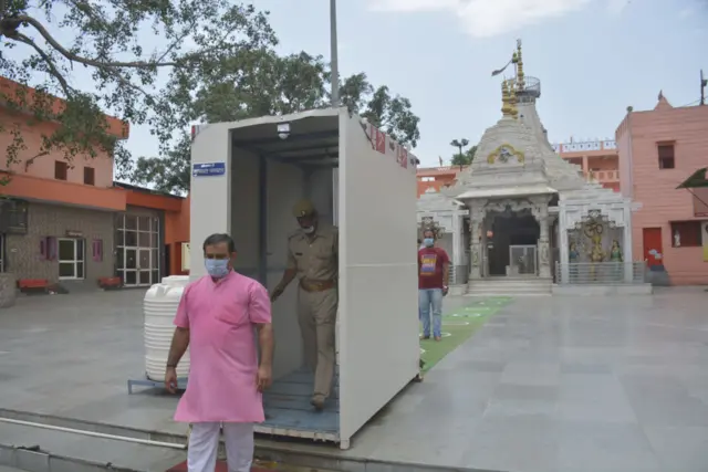 A man walks through a disinfection tunnel installed in Shri Dudheshwar Nath Temple ahead of its reopening, on June 7, 2020 in Ghaziabad, India.