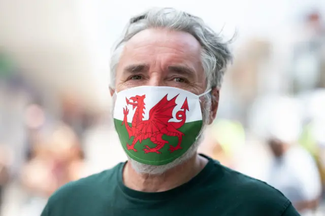 A man wears a Welsh flag facemask