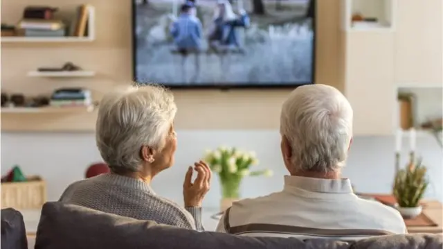 Two older people watch television