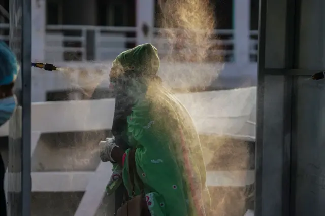 A woman walks through a disinfection tunnel, Dhaka, Bangladesh