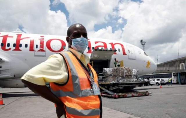 A man stands in front of an airplane