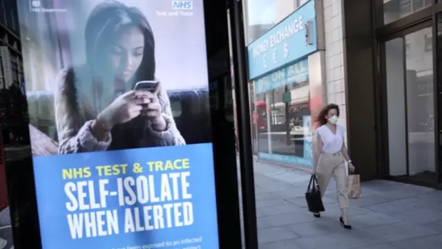 A woman walks past an NHS Test and Trace advertisement on Oxford Street as stores reopen following closure due to the coronavirus outbreak on 15 June 2020 in London