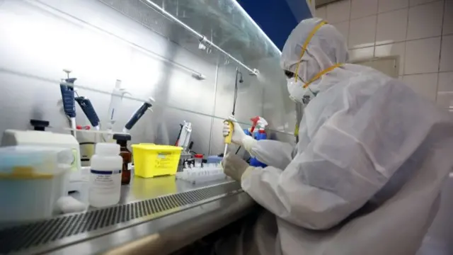 A lab technician wearing personal protective equipment (PPE) works on samples from suspected coronavirus patients at a laboratory in Sanaa, Yemen, 14 June 2020