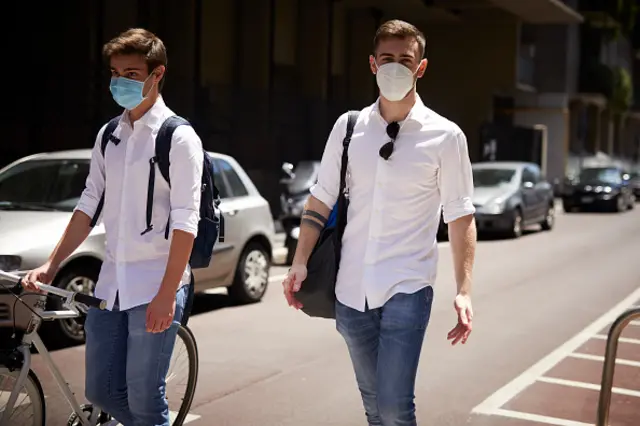 Two students wearing protective masks leave school in Milan