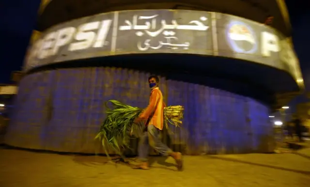 A man walk past closed shops during a restricted area that is sealed in smart lockdown, in Karachi, Pakistan, 18 June 2020