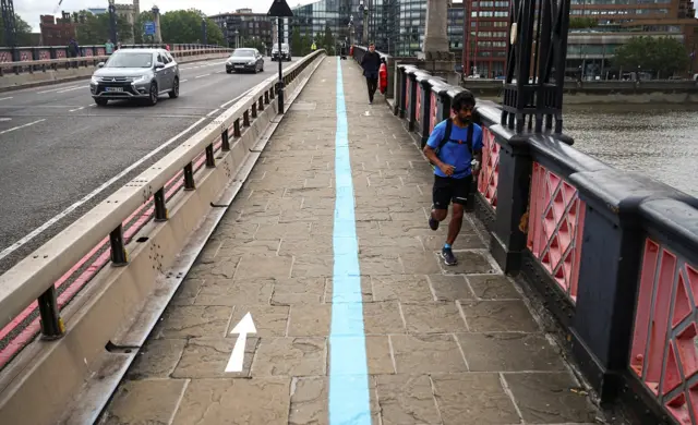 People follow social distancing markings as they cross Lambeth Bridge, as the outbreak of the coronavirus disease (COVID-19) continues, in London, Britain,