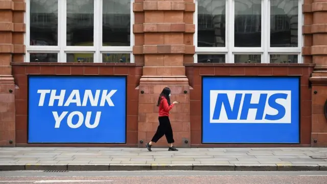 A woman walks past a sign thanking the NHS as she walks down a street in Manchester, north west England on June 19, 2020, during the novel coronavirus COVID-19 pandemic