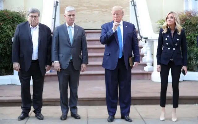 Donald Trump puts his finger to his lips as he stands in front of St. John's Episcopal Church across from the White House with U.S. Attorney General Bill Barr, National Security Advisor Robert O'Brien and White House Press Secretary Kayleigh McEnany