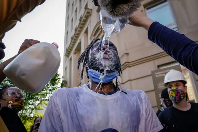 A demonstrator is doused with water and milk after being hit with pepper spray