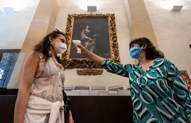 A woman undergoes a body temperature scanning procedure at the entrance of the Uffizi Gallery Museum in Florence