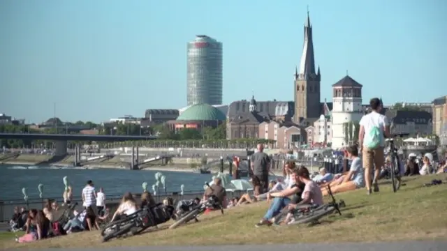 People sit on the banks of a river in Germany