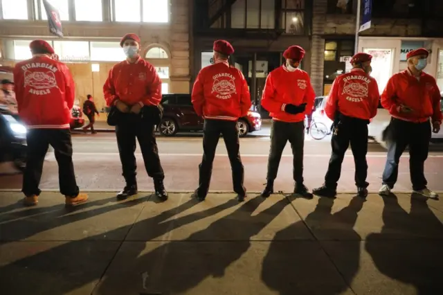 The Guardian Angels, a volunteer organisation of unarmed citizens, stand guard near looted stores