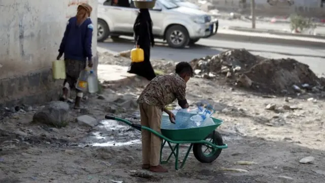 People fill water bottles at a communal tap in Sanaa, Yemen (1 June 2020)