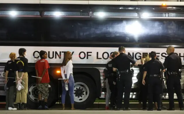 People stand handcuffed by police in the Hollywood area during emergency curfew in Los Angeles. Photo: 1 June 2020