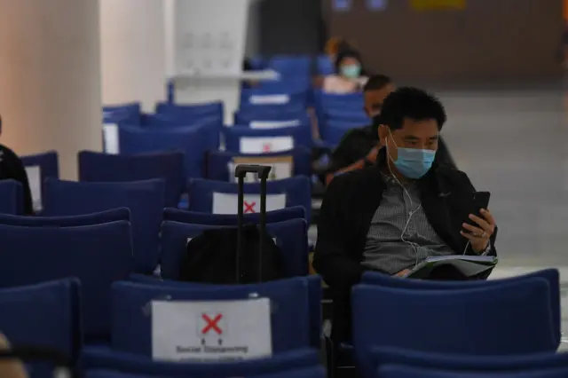 A passenger wearing a face mask waits for a flight at Bangkok airport