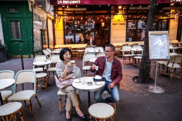 People drink coffee on a terrace in Paris