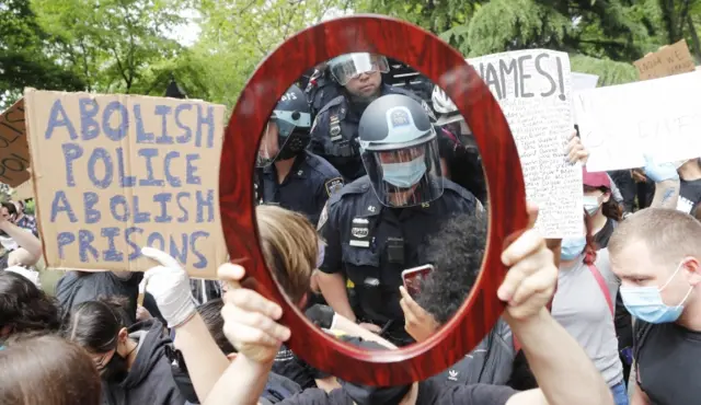 Police officer reflected in mirror held by protester