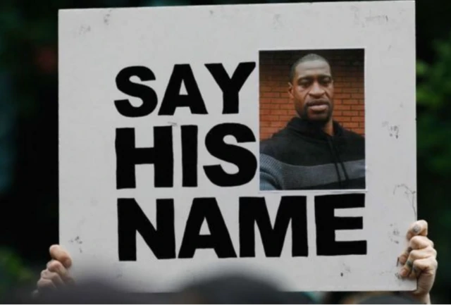 A protester holds a placard with a picture of George Floyd