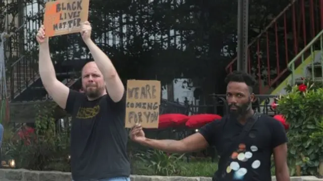 Two male protesters hold up signs, including one reading: "We are coming for you"