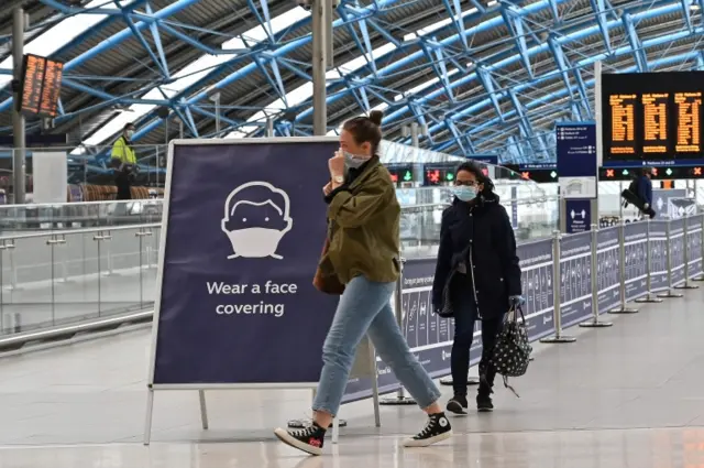 Passengers wear face coverings at a train station