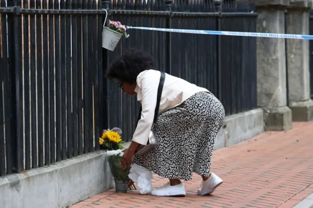 Woman leaves flowers at stabbing scene