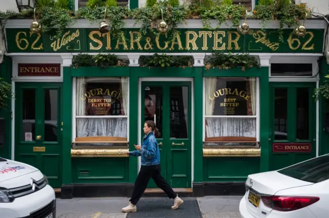 A woman walks past a temporarily closed pub on June 19, 2020 in London, England.