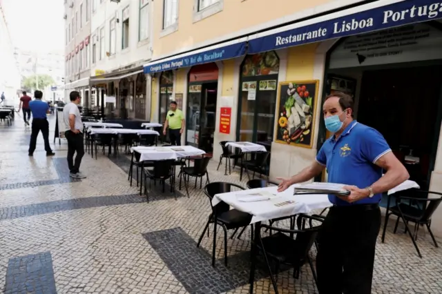 A waiter in Lisbon prepares a table outside