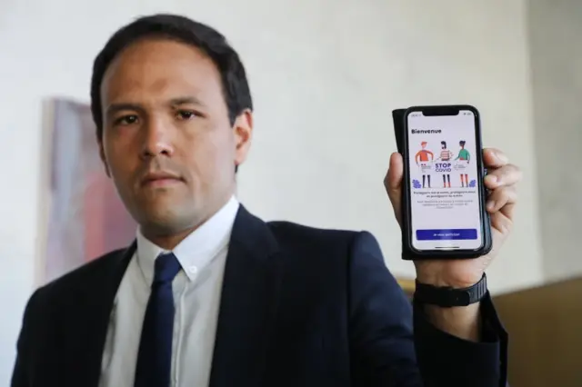 Cedric O holding a phone showing France's StopCovid tracing app