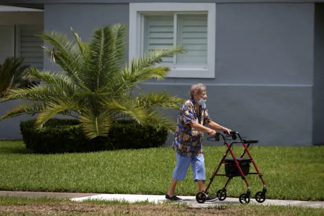 A woman wearing a protective mask walks in a street, as Miami-Dade County eases some of the lockdown measures put in place during the coronavirus outbreak, in Miami, Florida