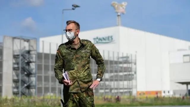 A soldier of the German armed forces Bundeswehr stands outside the headquarters of abattoir company Toennies in Rheda-Wiedenbrueck, western Germany