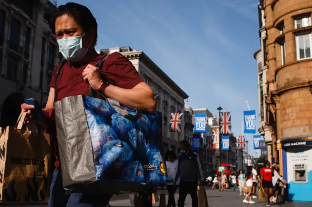 A shopper wearing a face mask carries bags along Oxford Street in London, England