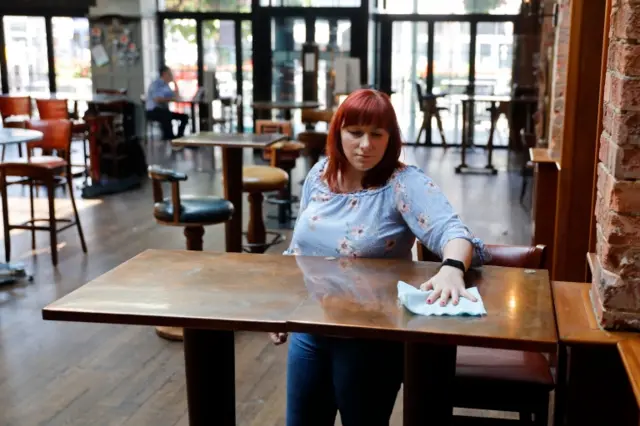 A staff member cleans a table at a Wetherspoon pub in north London on Wednesday