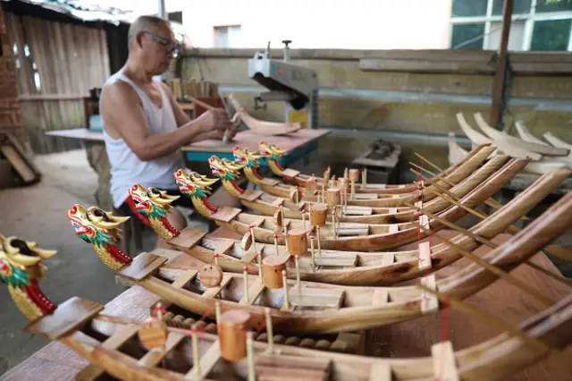 Dragon Head sculptor Zhou Chengyun carves a dragon boat to celebrate the traditional Dragon Boat Festival