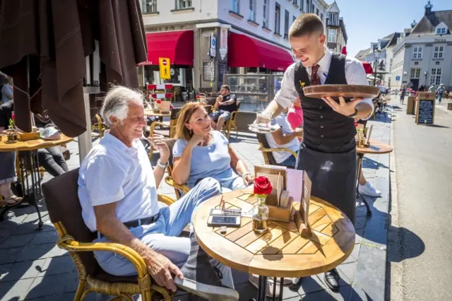 A waiter serves a couple at an outside table in Maastricht