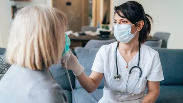 A care worker gives a woman a coronavirus temperature check